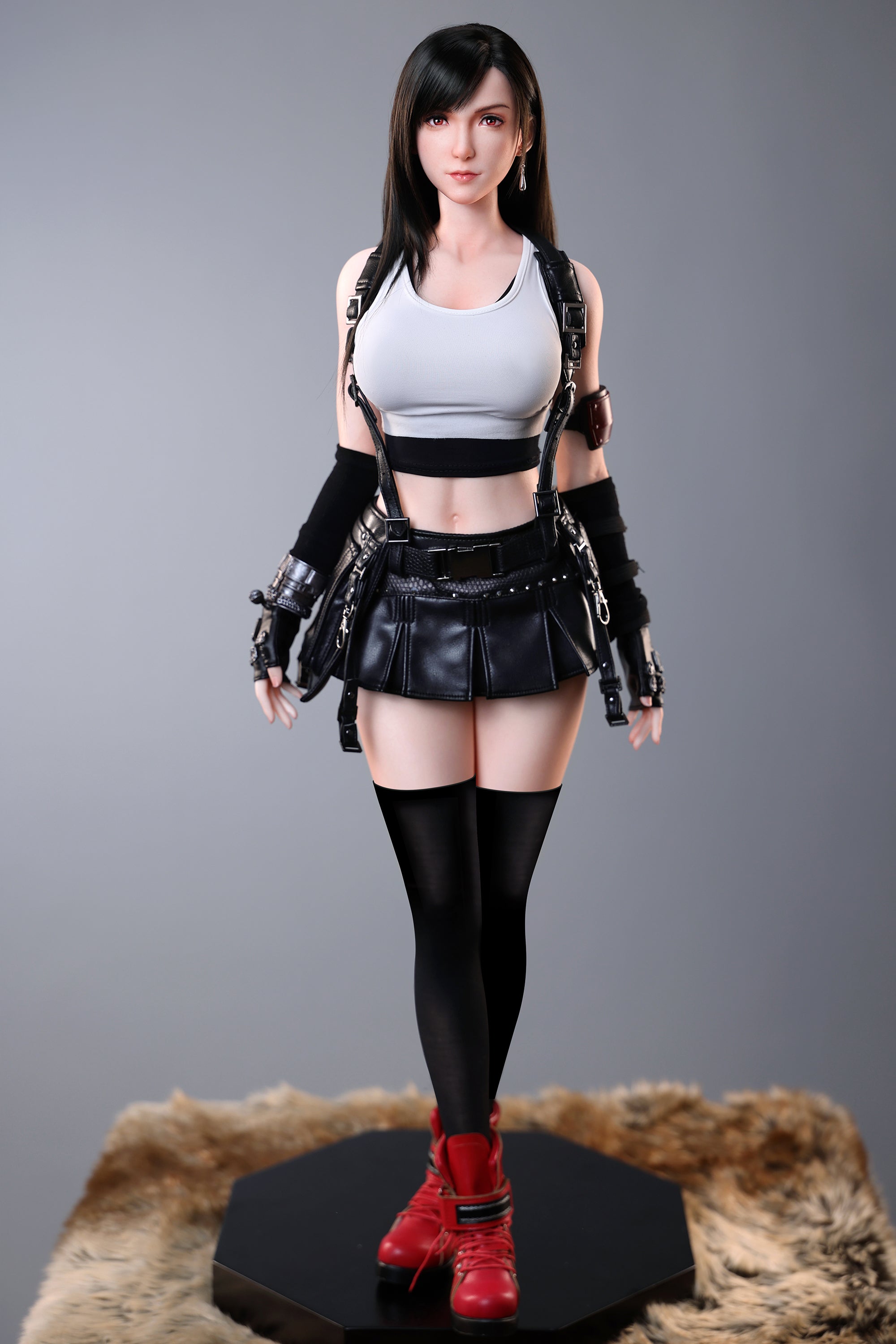 Action figure in a white tank top and black leather outfit on a gray
background, tifa